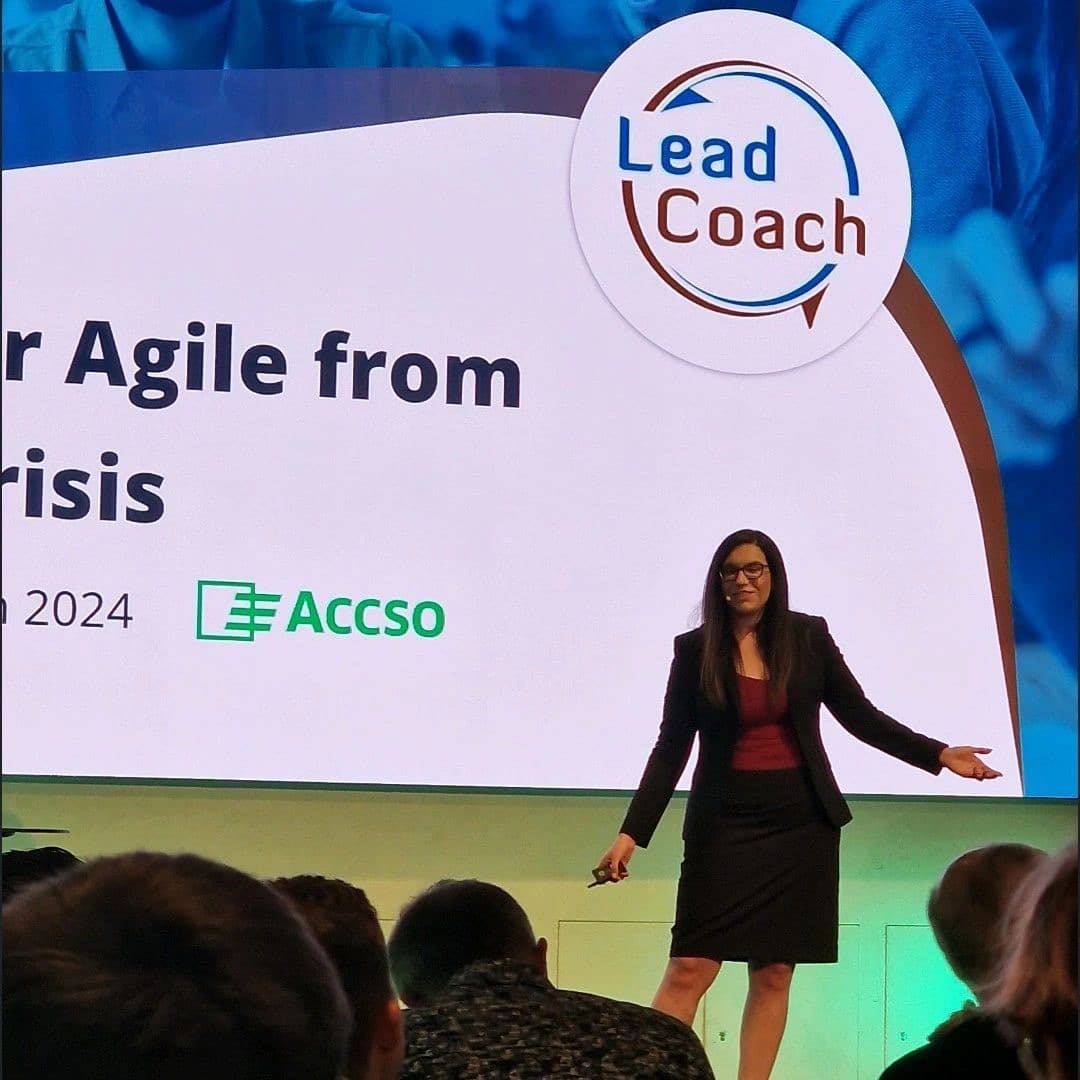 Bar Schwartz speaking on a conference stage in 2024, in front of a slide carrying the Lead2Coach mark